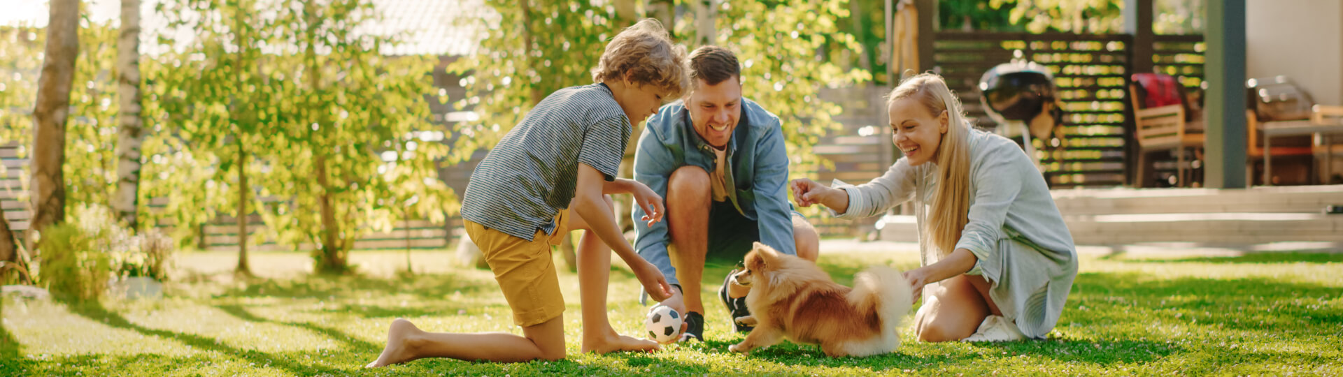Eine Familie spielt mit ihrem Hund im Garten Ball.