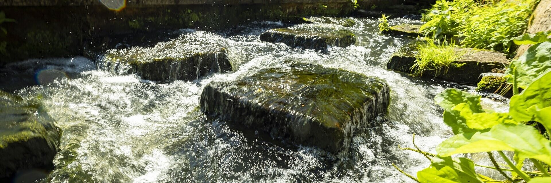 Ein mitreißender Fluss, indem große quadratische Steinblöck das fließende Wasser unterbrechen und stoppen