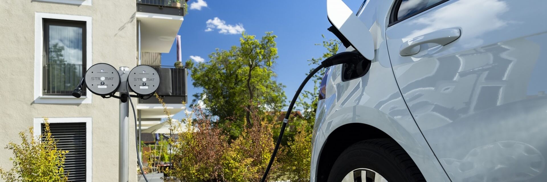 Eine Stromat-Anlage lädt ein Elektroauto vor einem Wohnhaus.