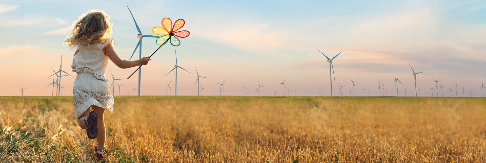 Ein Mädchen läuft über ein Feld. Im Hintergrund sieh man unzählige Windräder.